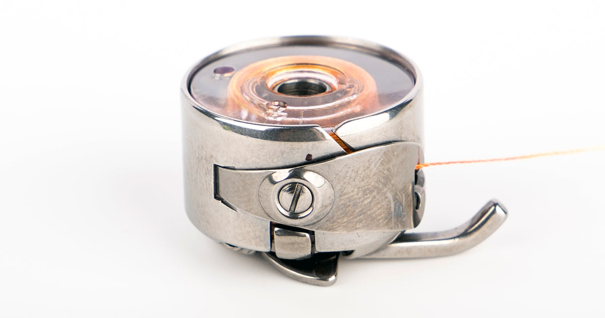 a metal class 15 bobbin case with a bobbin inside