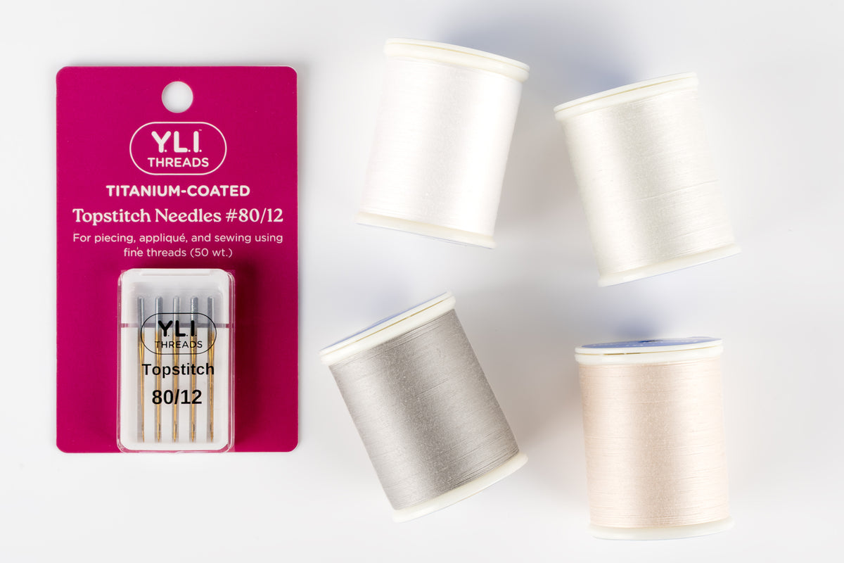 a set of four spools of dream seam 50 wt cotton thread and a pack of titanium-coated topstitch needles size 80/12