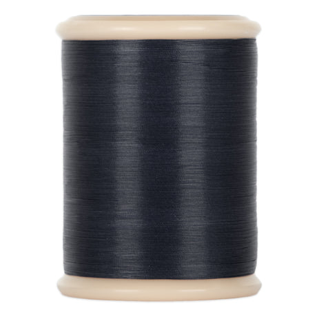 A spool of dark blue yli threads hand quilting thread on a 500 yd spool