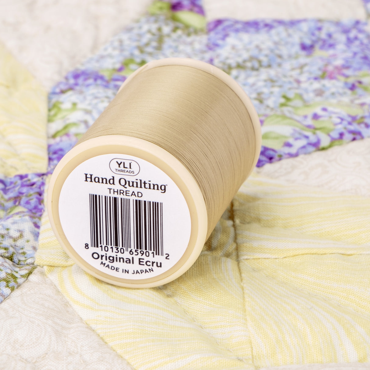 spool of original ecru hand quilting thread on a quit
