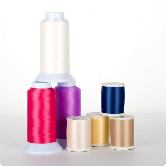 cones and spools of precision 60 wt. polyester thread on a white background
