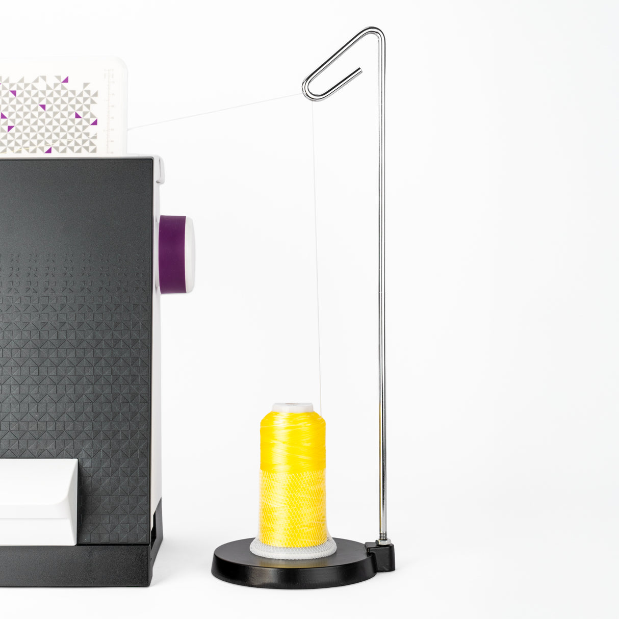 yellow cone of variations polyester thread on a metal thread stand next to a sewing machine