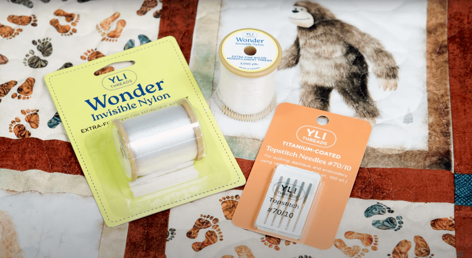 spools of wonder invisible thread and a package of topstitch needles on a quilt