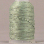 Soft green 12 wt jeans stitch thread wound on white plastic spool against neutral background