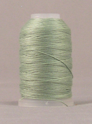 Soft green 12 wt jeans stitch thread wound on white plastic spool against neutral background