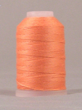 Peach colored thread wound on white plastic spool with pink cap