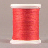 Red thread wound on white plastic spool against neutral background