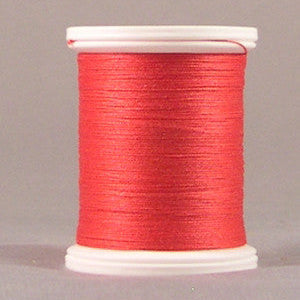 Red thread wound on white plastic spool against neutral background