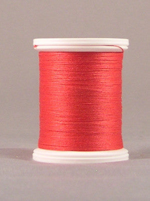 Red thread wound on white plastic spool against neutral background