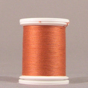 Orange thread wound on white plastic spool with visible thread layers and smooth finish