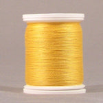 Yellow gold thread wound on white plastic spool with visible thread texture and smooth finish