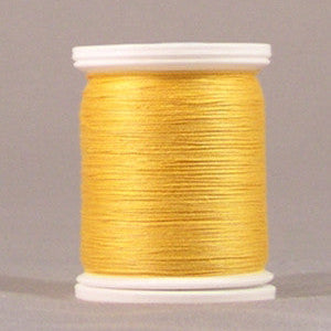 Yellow gold thread wound on white plastic spool with visible thread texture and smooth finish