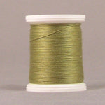 Green oregano colored thread wound on white plastic spool against neutral background