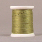 Green oregano colored thread wound on white plastic spool against neutral background