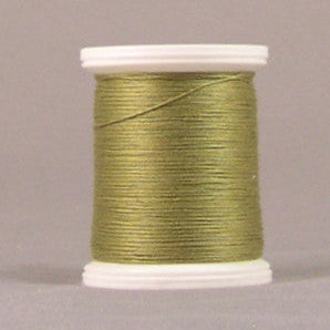 Green oregano colored thread wound on white plastic spool against neutral background