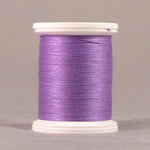 Lavender purple thread wound on white plastic spool against neutral background