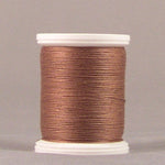 Nutmeg brown thread wound on white plastic spool against neutral background