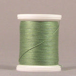 Green parsley colored thread wound on white plastic spool against neutral background