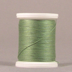 Green parsley colored thread wound on white plastic spool against neutral background