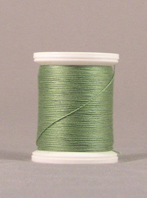 Green parsley colored thread wound on white plastic spool against neutral background