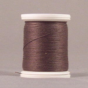 Dark brown thread wound on white plastic spool against neutral background