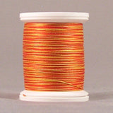 Orange and yellow variegated thread wound on white plastic spool against neutral background