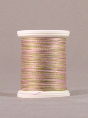 Variegated pink and green thread wound on white plastic spool against neutral background