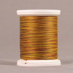 Orange metallic thread wound on white plastic spool with visible thread texture and shimmering finish