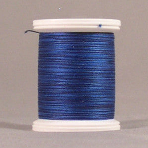 Blue thread spool with white plastic ends, showing tightly wound hyacinth blue thread on a neutral background
