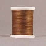 Brown thread wound on white plastic spool against neutral background