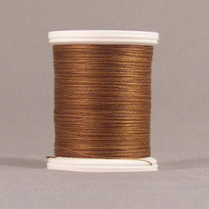 Brown thread wound on white plastic spool against neutral background