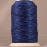 Blue variegated 24 wt thread on white cone spool with YLI label, showing deep navy to royal blue color variations