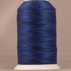 Blue variegated 24 wt thread on white cone spool with YLI label, showing deep navy to royal blue color variations