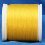 Yellow thread wound on white plastic spool against blue fabric background