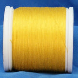 Yellow thread wound on white plastic spool against blue fabric background