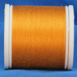 Gold thread on white plastic spool against blue background