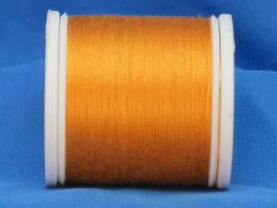 Gold thread on white plastic spool against blue background