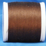 Brown thread wound on white plastic spool against blue background
