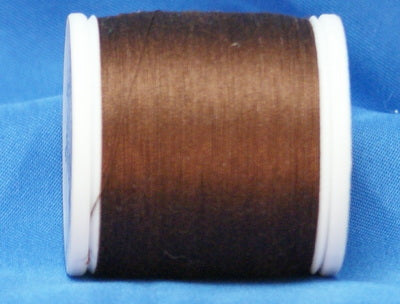 Brown thread wound on white plastic spool against blue background