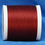 Red thread wound on white plastic spool against blue background