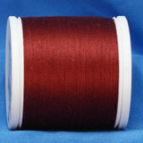 Red thread wound on white plastic spool against blue background