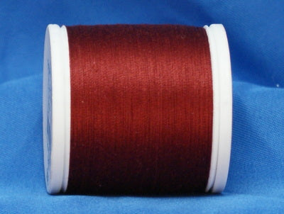 Red thread wound on white plastic spool against blue background