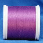 Magenta thread wound on white plastic spool against blue fabric background