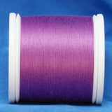 Magenta thread wound on white plastic spool against blue fabric background