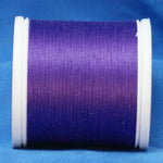 Purple thread wound on white plastic spool against blue fabric background