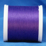 Purple thread wound on white plastic spool against blue fabric background