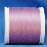Pink gradient thread spool on white plastic bobbin against blue fabric background