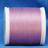 Pink gradient thread spool on white plastic bobbin against blue fabric background