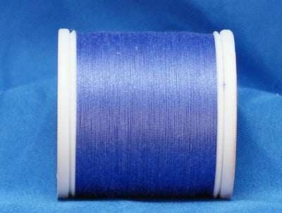 Lilac purple thread wound on white plastic spool against blue background