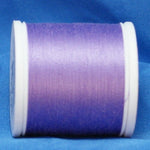 Lavender purple thread on white plastic spool against blue fabric background
